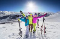 Female and male young people having skiing and snowboarding vacation on a snow slopes